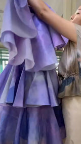 Person holding a purple layered dress with a blurred background