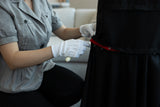 Person wearing gloves adjusting a red belt on a black garment.