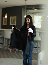 Woman holding a black garment in a modern interior setting
