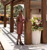 Woman standing under a wooden pergola with a decorative planter nearby