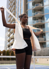 Woman exercising with resistance bands on a tennis court with buildings in the background